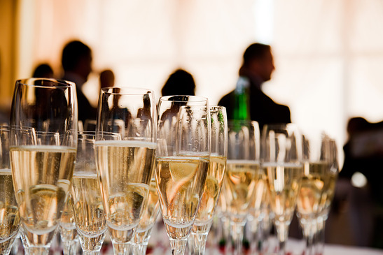 Image: Table of full champagne glasses with people in background