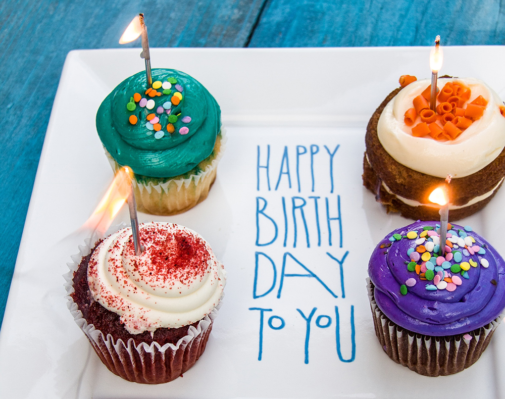 Happy Birthday written on a plate with cupcakes.